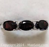 Close-up of the garnet stones on the sterling silver ring, showing three deep red oval garnets set in a row.