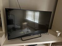 Front view of 43-inch Sony Bravia TV showing reflective screen and stand.