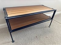 Front and side view of adjustable height shoe rack with black metal frame and wooden shelves.