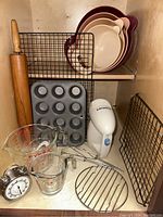 Photo showing entire baking and mixing lot including hand mixer, measuring cups, timer, cooling racks, muffin tin, wooden rolling pin, and nested bowls.