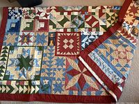 Full view of the quilted bedspread showing a variety of star patterns and cat applique squares in multiple colors with a red border.