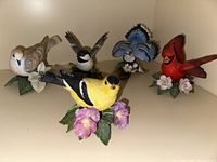 Front view of all five Lenox bird figurines showing the range of colors and bases with flowers.