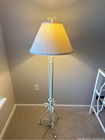 Full view of iron floor lamp painted white with beige fabric lampshade, approximately 61 inches tall.