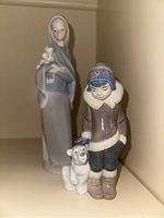 Front view of both Lladro figurines on a shelf, showing the Lady with Calla Lilies holding flowers and the Inuit boy standing beside the polar bear.