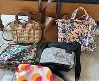 Full group shot of five purses and bags showing variety of colors and styles.
