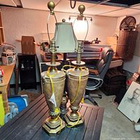 Pair of large matching ornate table lamps with brass bases and yellow cords on a table