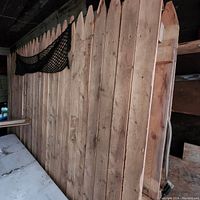 Full view of five vertical wooden fence panels with pointed tops, stacked upright.