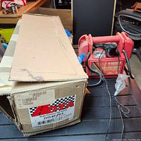 Car strut in original box placed next to the battery charger.