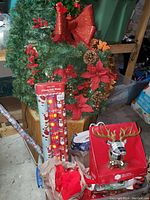 Photo showing the Christmas wreath with poinsettias, pine cones and bow, gift wrap rolls, gift bags, and decorative reindeer item