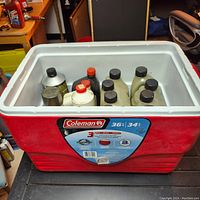 Full view of red Coleman cooler filled with motor oil and two stroke oil bottles