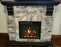 Front view of electric fireplace heater showing flame effect, stone veneer surround, and dark wood mantel.