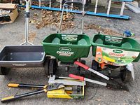 Lot showing two Scotts Deluxe EdgeGuard broadcast spreaders, black plastic garden cart, and three pairs of hedge clippers/loppers.