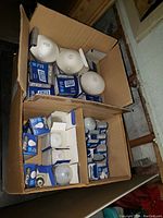 Box containing multiple GE light bulbs in packaging and some loose bulbs