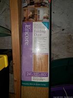 Close-up photo showing packaging label with brand name 'Encore' and product details including dimensions 24x32x80 inches and features like energy efficient double vinyl panel and flexible vinyl hinges.