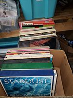 Photo showing a box containing a large stack of assorted music records with sleeves visible, front album titled 'Stardust 108 All-Time Favorites'.