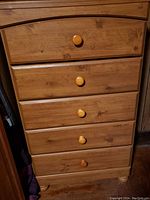 Front view of the tall wooden dresser showing the five drawers with round wooden knobs and natural wood finish.