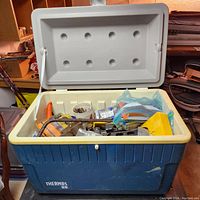 Opened blue and white Thermos cooler showing an assortment of tools and hardware inside.