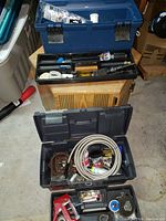 Two toolboxes on floor filled with various plumbing supplies and tools