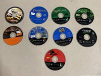 Photo showing the 10 Nintendo GameCube game discs arranged on a flat surface. Disc titles visible include F1 World Grand Prix, Lord of the Rings, Sarge's War, Sonic Heroes, Splinter Cell, among others.