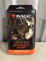 Front side of sealed Magic the Gathering Innistrad Midnight Hunt draft pack featuring werewolf artwork and product branding.