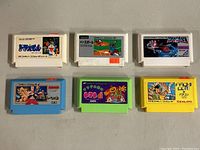 Six vintage Japanese Famicom video game cartridges in various colors on neutral background.