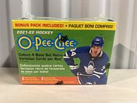 Front view of sealed 2021-22 O-Pee-Chee hockey trading card box featuring player image and text about packs and cards included.