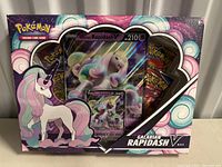 Front view of sealed Galarian Rapidash V box with large holographic card and booster packs inside packaging