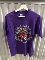Front view of purple Toronto Raptors T-shirt with large dinosaur logo on chest.