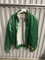 Front of green satin jacket with ribbed collar and cuffs, showing open front and white lining.