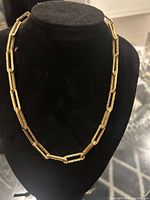 Full view of gold paper clip chain displayed on black bust