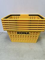 Six yellow plastic shopping baskets stacked, showing the RONA logo on the side and ventilation holes.
