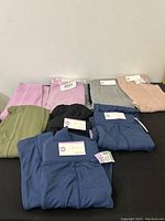 Eight pairs of medium-sized girls leggings in assorted colors including pink, gray, green, black, and blue shown folded with tags attached.