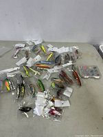 Overview of 21 individually bagged hard-bodied fishing lures spread on table