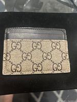 Front side of Gucci card holder showing GG Supreme canvas pattern with black leather trim.