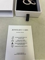 Close-up photo showing the jewelry care instruction card from Tempête with guidance for storing and maintaining the earrings.