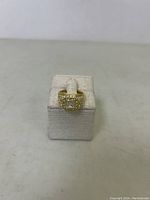 Front view of men's size 8 ring showing the square center stone and clear stone accents, displayed on a beige fabric stand.