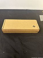 Top view of sealed rectangular brown cardboard box showing a plus sign on top.