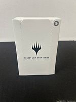Front view of sealed Magic: The Gathering Secret Lair Drop Series pack, white box with logo and age recommendation (13+).