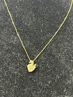 Close-up of the gold plated swan pendant with crystals on a black surface