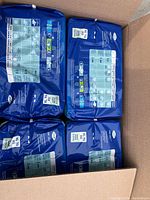 Four sealed packs of TENA ProSkin briefs, size XL TG, each pack with 15 briefs, in a cardboard box.