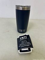Black YETI Rambler tumbler with silver rim and clear lid, showing YETI logo on bottom part.
