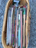 Top view of wooden basket filled with paper packages of incense sticks and cones viewed from above showing multiple colorful packages packed vertically.