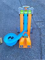 Photo from top view showing the three orange lanes, blue spiral track on the side, and three green car launchers at the top with Hot Wheels branding.