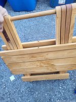 Folded foldable wooden table showing slatted wooden top and folded legs.