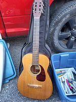 Full view of a classical-style acoustic guitar with six nylon strings and tortoiseshell pickguard.