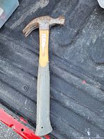 Photo showing a single claw hammer with a rubber handle and rust on the metal head