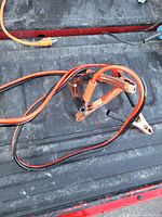 Jumper cables coiled on truck bed with visible copper clamps and red and black cables.