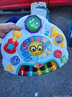 Single handheld photo of a colorful children's activity toy with musical and educational features.