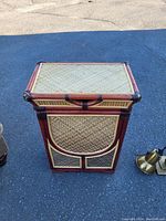 Front view of the laundry basket showing woven wicker panels framed by reddish bamboo poles with a closed hinged wooden lid.