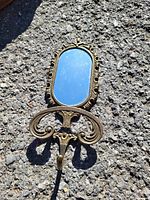 Single wall mirror with ornate gold-tone frame and decorative dual hooks